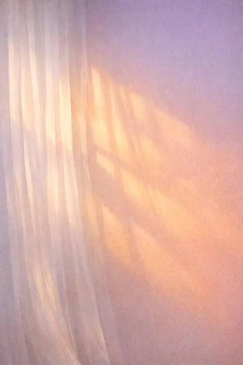Aesthetic wallpaper of warm sunset light falling through a sheer curtain onto a bare wall