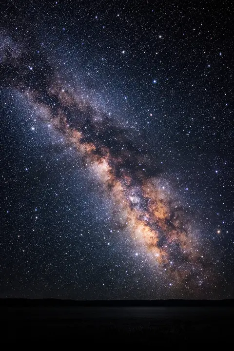 Space wallpaper with the Milky Way arching over a dark horizon under thousands of stars