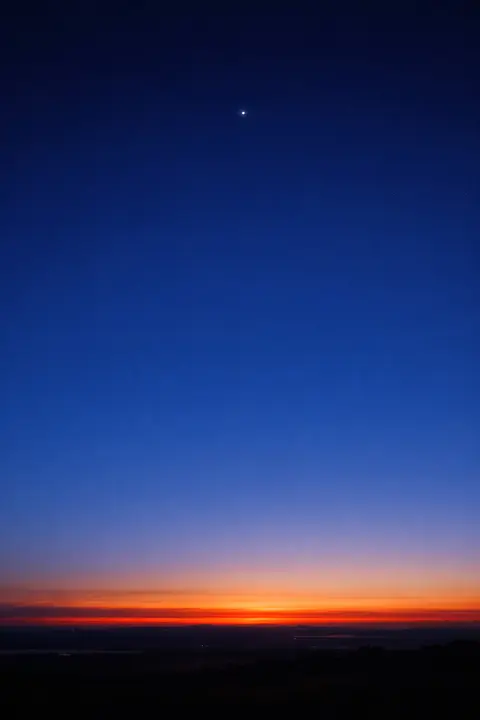 Sunset wallpaper just before dusk with a deep blue sky, a warm horizon band and one star