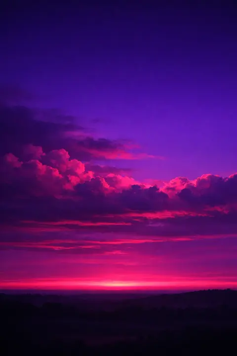 Purple sunset wallpaper with magenta clouds on deep violet and a pink band at the horizon