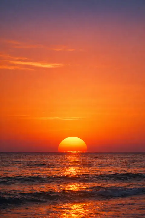 Sunset wallpaper at the moment a large flattened sun disc is half swallowed by the sea